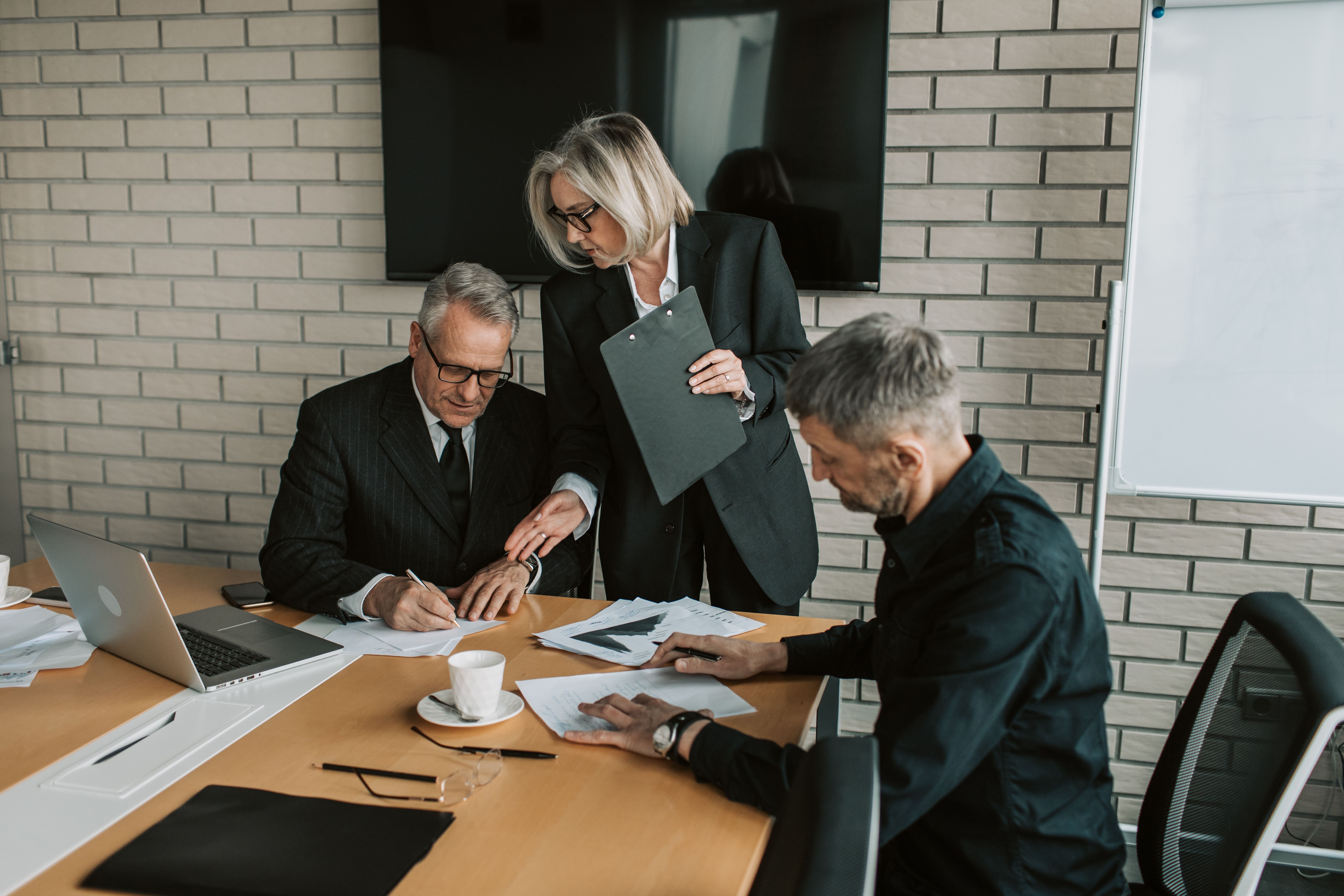 Business professionals signing a tuition reimbursement agreement in an office meeting
