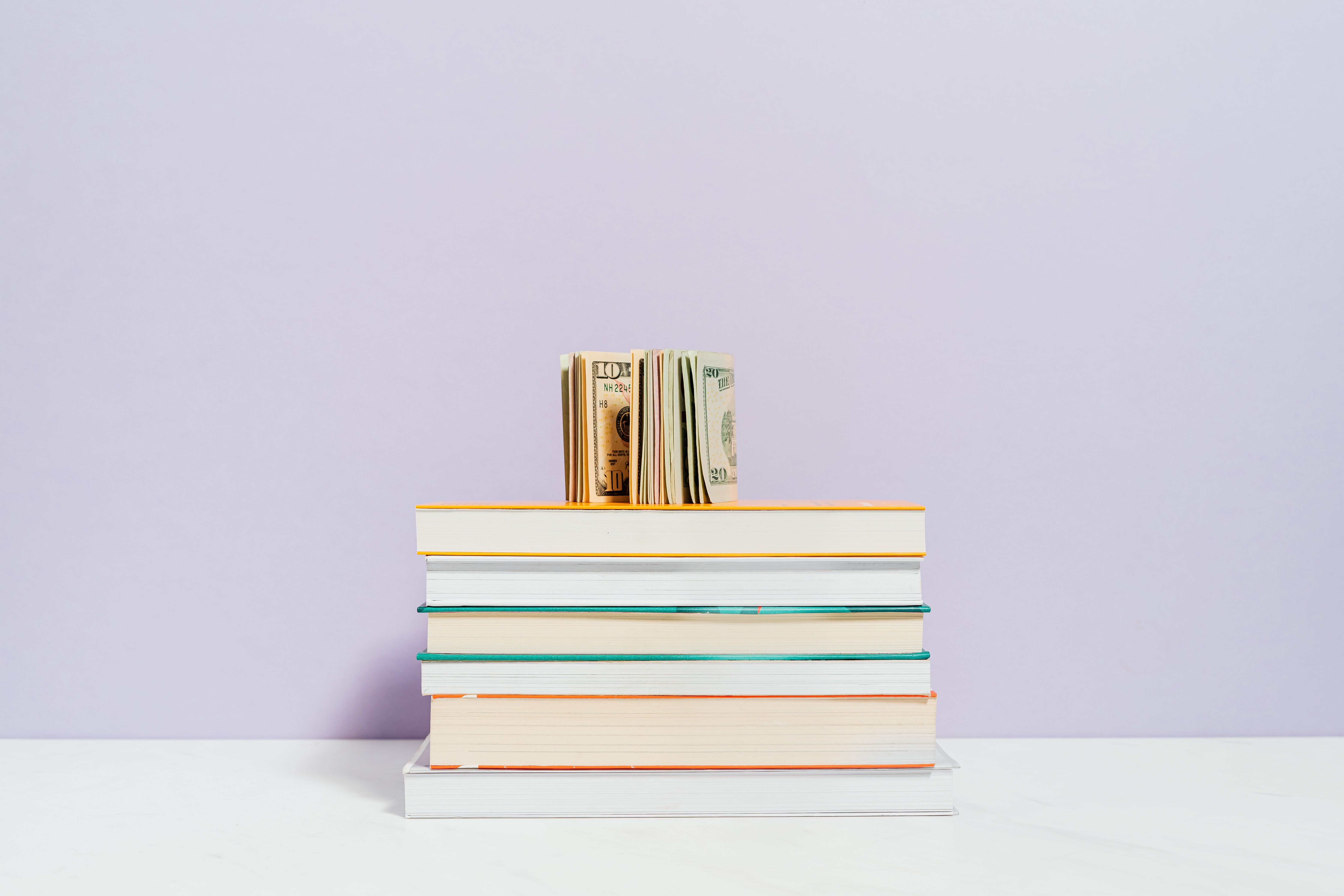 Stack of textbooks topped with US dollar bills representing the hidden cost of an MBA
